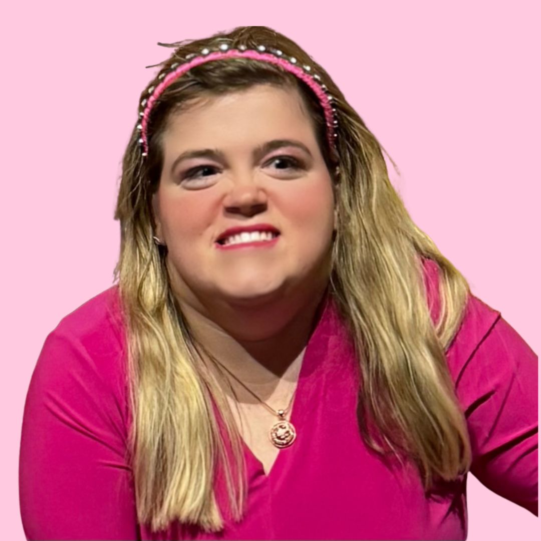 Marisa Conners smiling, wearing a bright pink top and a pink pearl headband against a pink background.